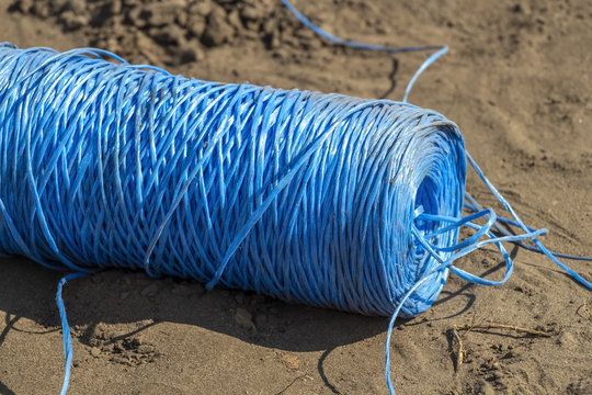 A string of blue synthetic rope in the sand.