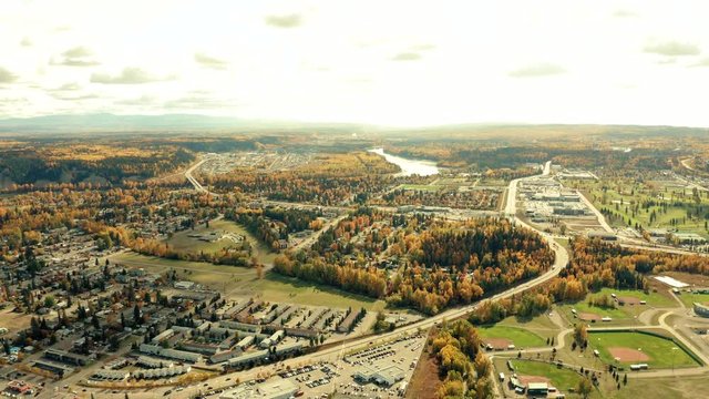 A cinematic, aerial view of the city of Prince George downtown area, including multiple residential areas and some inner-city nature during the autumn / fall season.
