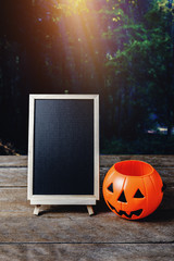 Halloween background. Spooky pumpkin, chalkboard on wooden floor with moon and dark forest. Halloween design with copyspace
