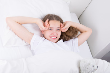 girl in white bed, smiling, waking up early in the morning