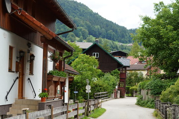 well-groomed cozy street with a low decorative fence in the Austrian city in the Alpine mountains, in the foreground white wall of the house with wooden elements, brown cornice and tides