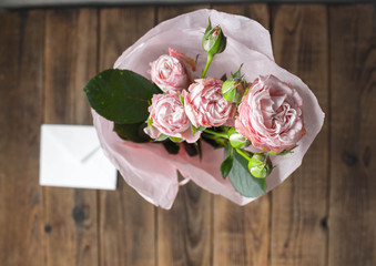 a roses in a vase with envelope on wooden grey background