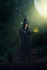 woman in Black Scary witch halloween costume with moonlight in a dark forest