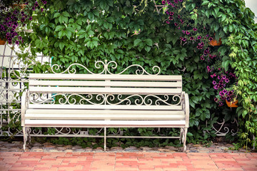 White bench stands in the Park among the flowers 