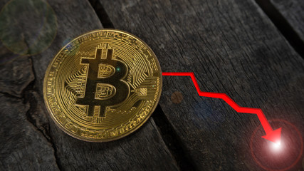 ฺBitcoin coin on the wood table have Red arrow pointing down and light at the end, Concept down...