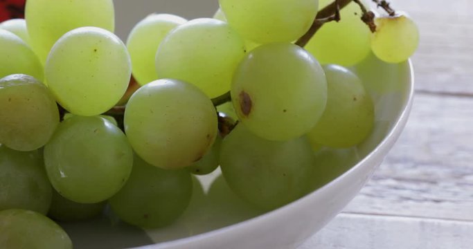 Fresh grape cluster in plate ready for eating. Close-up, panning right
