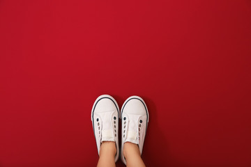 Legs of girl wearing shoes on color background