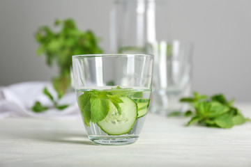 Glass of tasty fresh cucumber water on white table
