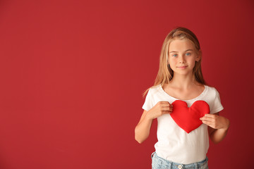 Cute little girl with red heart on color background