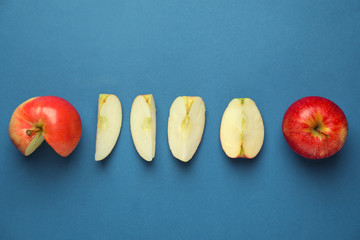 Cut and whole ripe fresh apples on color background