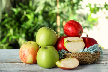 Bowl with cut and whole fresh apples on light wooden table