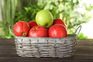 Basket with ripe fresh apples on wooden table