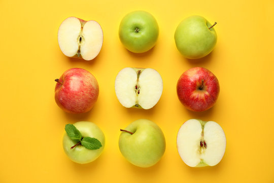 Cut and whole apples on color background