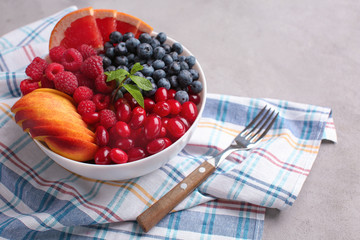Plate with delicious fruit salad on grey table