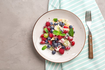 Plate with delicious fruit salad on grey table