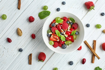 Plate with delicious fruit salad on white wooden table