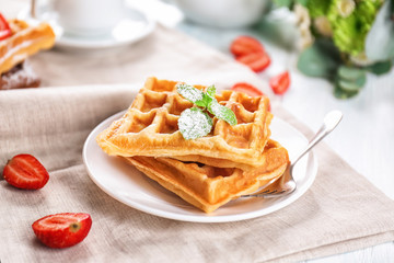 Plate with delicious waffles on table