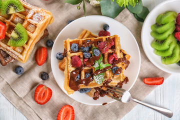 Delicious waffles with berries and chocolate sauce on plate