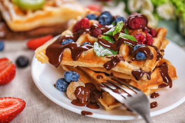 Delicious waffles with berries and chocolate sauce on plate