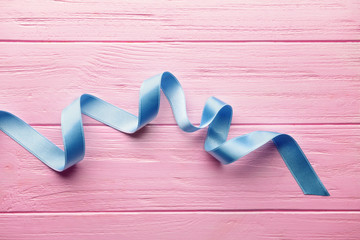 Beautiful blue ribbon on color wooden table