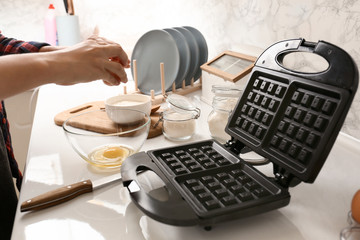 Fototapeta na wymiar Woman making dough for waffles in kitchen