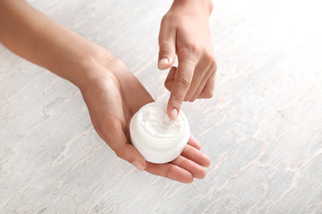 Young woman applying body cream, closeup