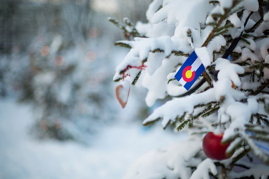Colorado state flag. Christmas background outdoor. Christmas tree covered with snow and decorations and Colorado flag.  New Year / Christmas holiday greeting card.