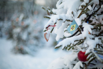 Delaware state flag. Christmas background outdoor. Christmas tree covered with snow and decorations...