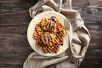 Plate with delicious waffles and ice cream on wooden table, top view