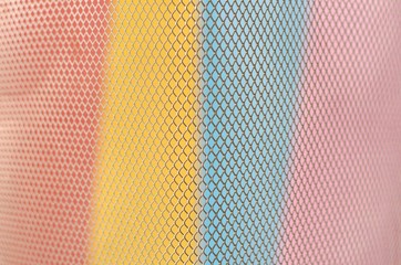 Colorful papers which are red, yellow, blue and pink with partial focus of the grid pattern of paper bin that design as modern background and wallpaper.