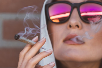 Portrait of a girl smoking marijuana joint on the street of Amsterdam (Holland - Netherlands) -...