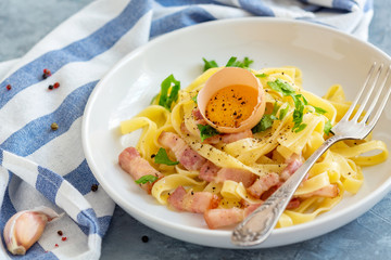Pasta Carbonara with egg yolk and fork in the plate.