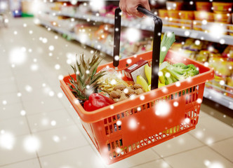 sale, shopping, consumerism and people concept - woman with food basket at grocery store or supermarket over snow