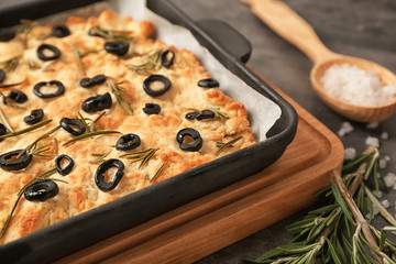 Baking tray with traditional Italian Focaccia on wooden board