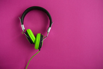 Modern headphones on color background