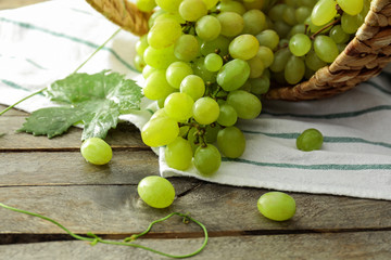 Overturned basket with ripe juicy grapes on wooden table