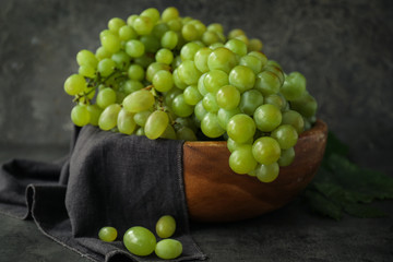 Bowl with ripe juicy grapes on grey table