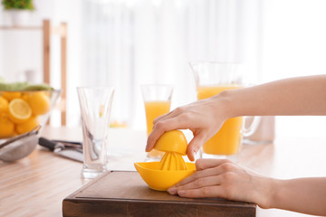 Woman squeezing fresh lemon juice in kitchen