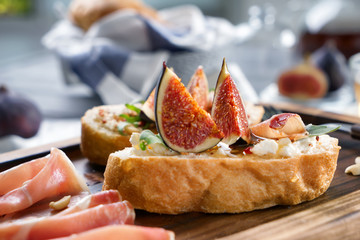 Tasty sandwiches with ripe fig and prosciutto on wooden board, closeup
