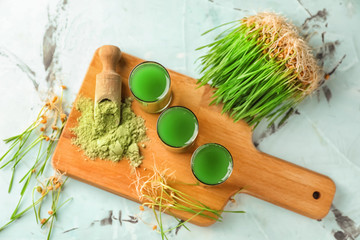 Glasses of fresh wheat grass juice on wooden board