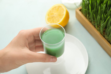 Woman holding shot of wheat grass juice, closeup