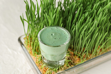 Sprouted wheat and glass of healthy grass juice on white table