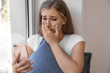 Lonely worried woman with mobile phone at home