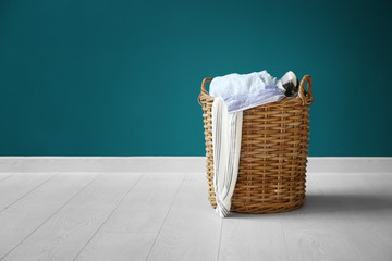 Laundry basket with dirty clothes on floor near color wall