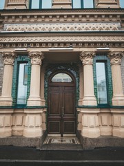Obraz premium The facade of the historic old building with a large wooden door, columns and green brick