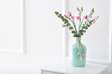 Vase with beautiful pink flowers on table near white wall