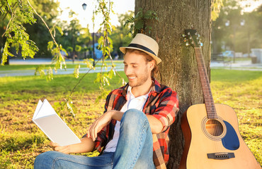 Handsome young man with book resting in park