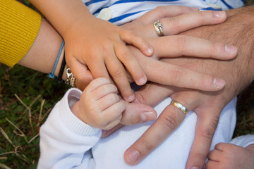 Baby hand in mother father children hands outside in grass