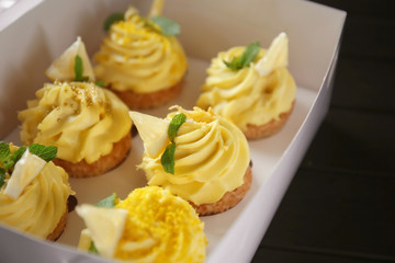 Fototapeta na wymiar Delicious lemon cupcakes in box, closeup