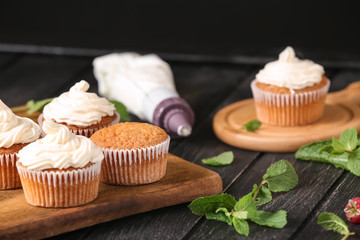 Delicious cupcakes and pastry bag on wooden board